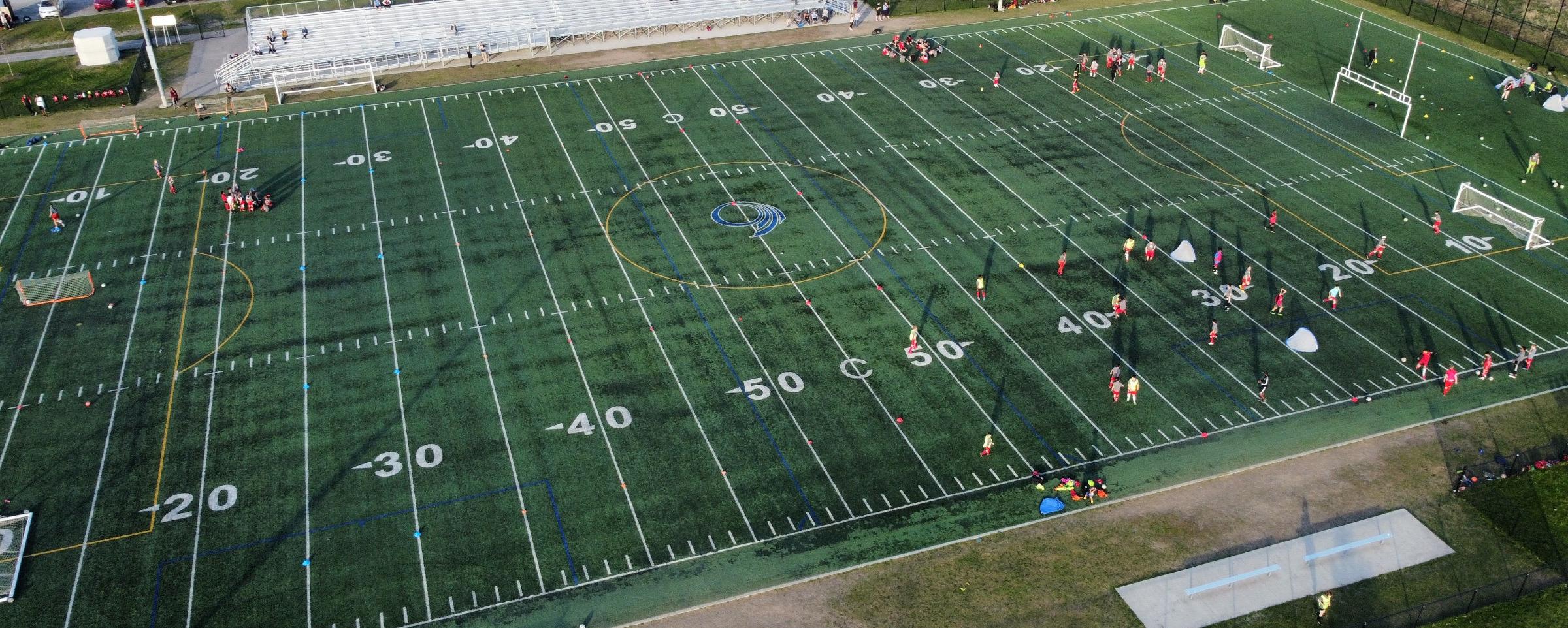 Football field with players and equipment, including a goal post and bench.